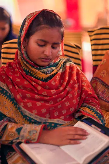 A young woman reads aloud from her own Bible